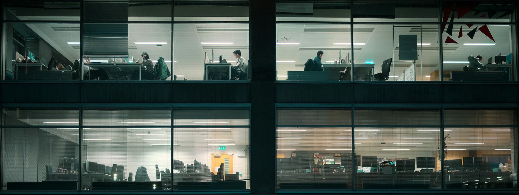Bürogebäude am Abend, hinter den erleuchteten Fenstern wird gearbeitet
